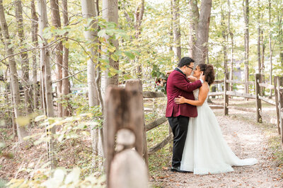 Bride and groom stand on nature path embracing and smiling at eachother
