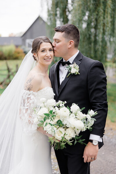 Bride and Groom going in for a kiss during portraits at Stonefield Estates wedding venue in Ottawa, Ontario. Photographed by Destination Wedding Photographer, Brittany Navin Photography