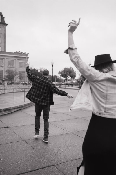 Couples twirls and dances in courtyard during their engagement photoshoot