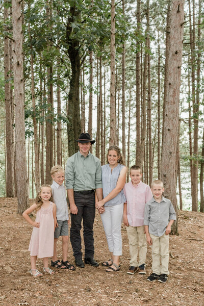 family of six standing in the woods smiling