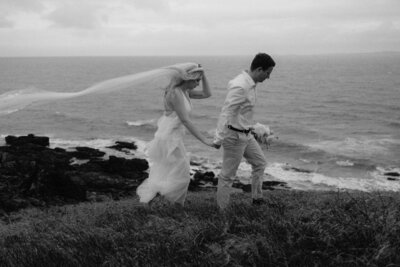 Yeppoon Elopement On a cliff over looking the ocean. Bride and Groom walking on cliff very windy