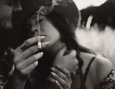 Woman smoking a cigarette that her lover is holding for her.