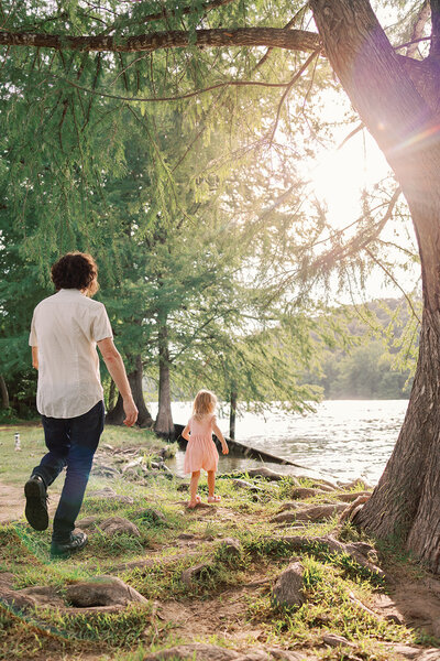 A dad and his daughter run around at Commons Ford during a family photo session in Austin, Texas