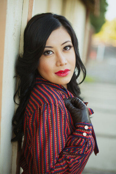 An Asian travel agent wearing a vintage silk shirt and black gloves for a personal branding photoshoot.
