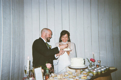 Victoria Barclay, photographer at Through Victoria's Lens, and her husband cutting cake on their wedding day