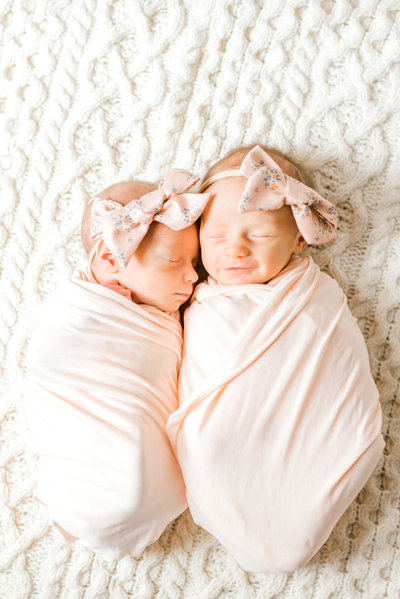 Newborn twin girls in pink swaddles