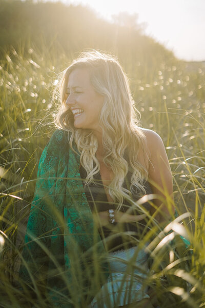 Katie, a spiritual entrepreneur coach, smiling joyfully in the middle of a grassy field, embodying the essence of a modern mystic.