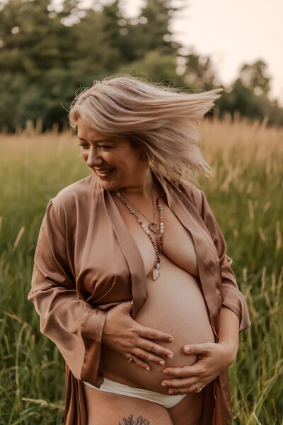 Women holding pregnant belly in joyful moment during maternity session in Wheaton, IL