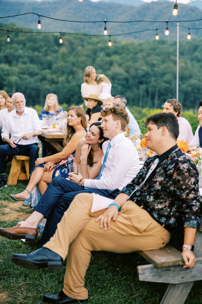 The bride and groom cuddle while listening to the speeches during the reception of their wedding at scenic venue Paint Rock Farm in North Carolina, by photographer Megan Lynn of My Sun and Stars Co.