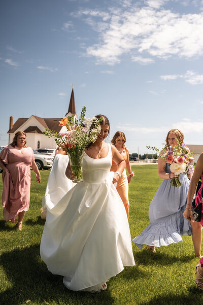 A bride and her bridesmaid walking to a church to get married.