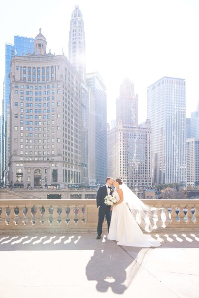 Bride and groom kissing at the Wrigley building for their photos by Chicago wedding photographer Winterlyn Stebner