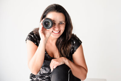 photo of a brand photographer holding a lens close to one of the eyes