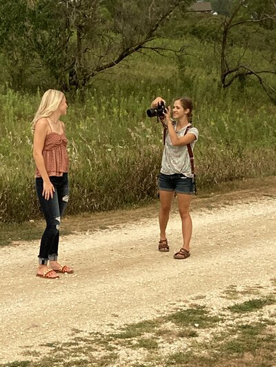 Omaha Wedding Photographer Anna Brace smiles at the camera while wearing blue jeans and a grey top