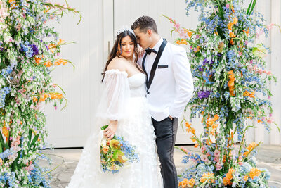 A close-up, intimate wedding portrait of a beautiful bride wearing a delicate floral headpiece, gazing softly, as the groom in a crisp white tuxedo leans in. A moment of love and elegance, perfect for capturing the essence of romance.