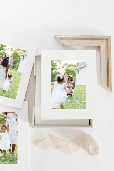 A photoshoot of a mother and two daughters playing in the field. The mother is bent down while holding the baby as her older daughter runs towards them.