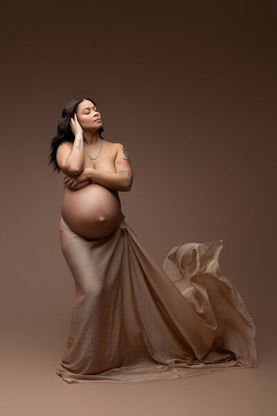 pregnant mom posed on the ground in a pink gown