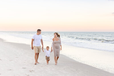 a family of three walking at beach near Norfolk, VA