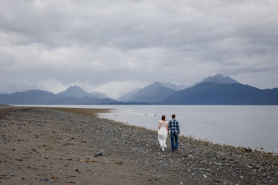 Moments after their wedding ceremony, a young couple walks down a rocky beach of the Cook Inlet in Homer, Alaska
