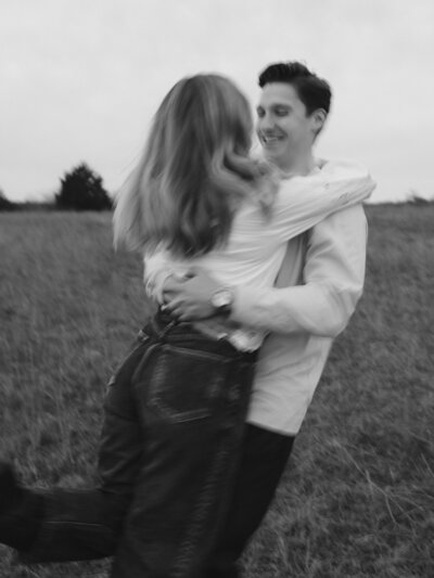 Close up image of couple with their arms around each other on a dark studio background