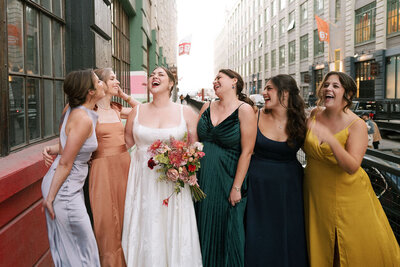 Bride and her bridesmaids laughing on a city street