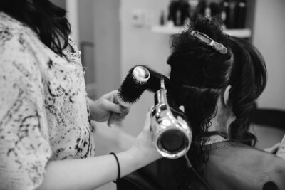 Liz Colasurdo, owner of Artisan Salon, blow dryer hair for a client