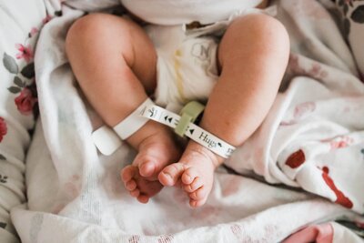 Infant's legs and feet with hospital id bracelets in a newborn and family photoshoot.