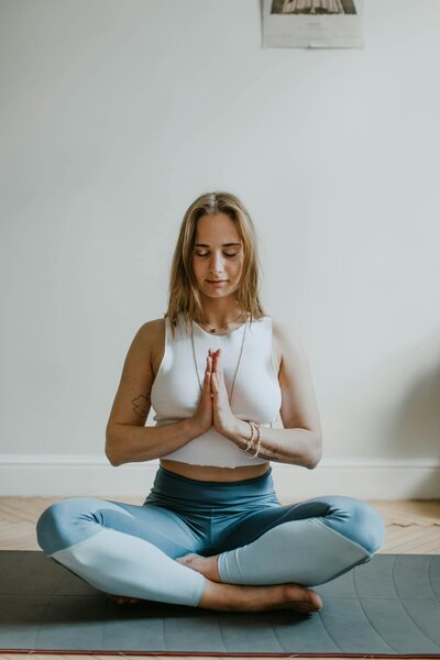 A woman with her eyes closed and hands at her heart doing yoga.