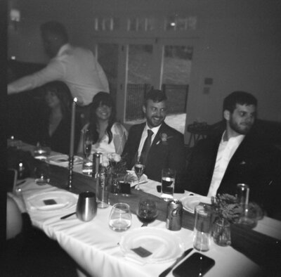 film photo of bride and groom at dinner table on their wedding