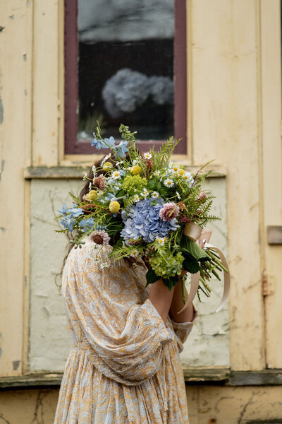 Pittsburgh wedding florist Heavenly Blooms hiding her face behind a large floral bouquet 