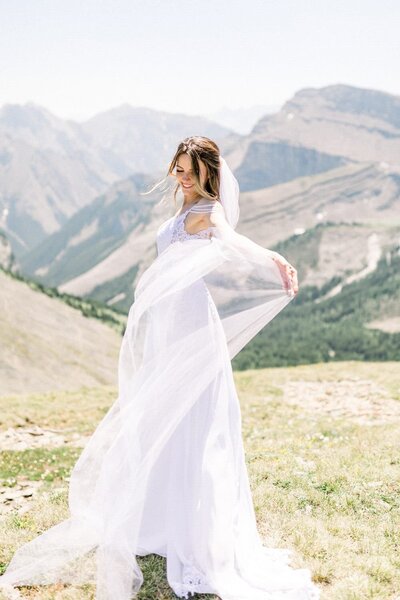 This joyful photograph captures a bride playfully twirling her dress during her mountain wedding after arriving by helicopter. The dramatic alpine backdrop and her carefree movement perfectly reflect the adventurous and celebratory spirit of their special day.