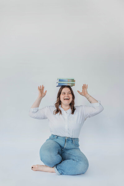 Woman laughing while balancing books on her head