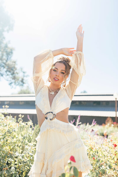 high school girl wearing all white outfit with puffy sleeves posing for picture with her hands up