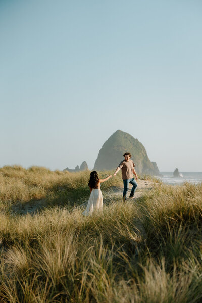 A couple holds hands in front of a coastal view during their elopement