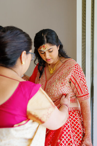 A person helping pin their child's wedding dress to them 
