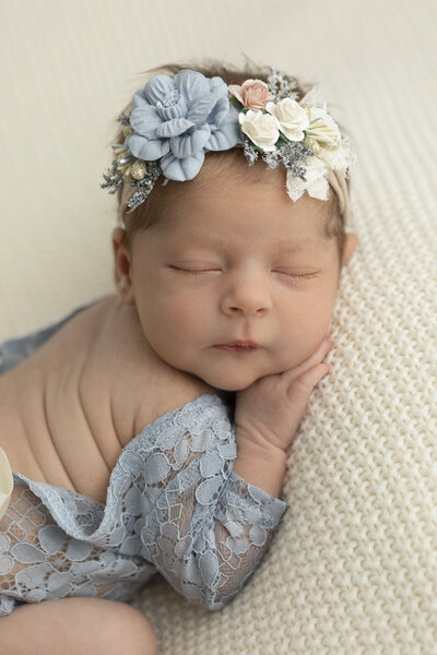 newborn baby smiling with white bow on her head