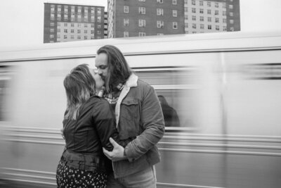 couple kissing as train drives by in NYC