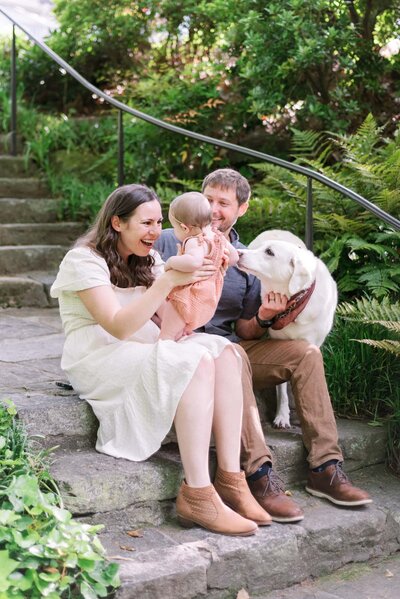 A family and their dog giggle with their little daughter