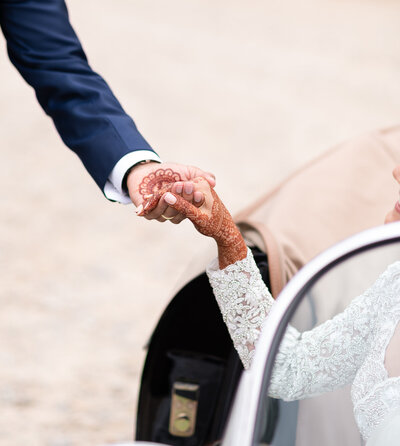 Groom gently grabbing brides hand to ease her out of the car