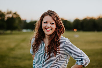 Maryland wedding photographer headshot with woman in a blue and white striped shirt with her hands on her hips smiling