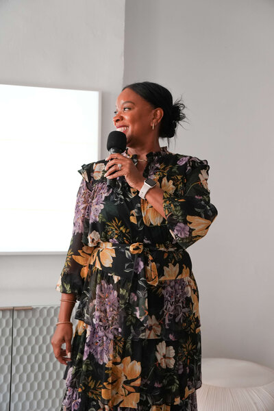 jacinta-gandy-speaking-holding-microphone-in-floral-dress-05