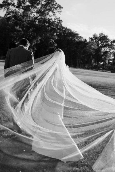 photograph in minnesota by tom thornton photography of bride twirling wedding dress and veil in black and white