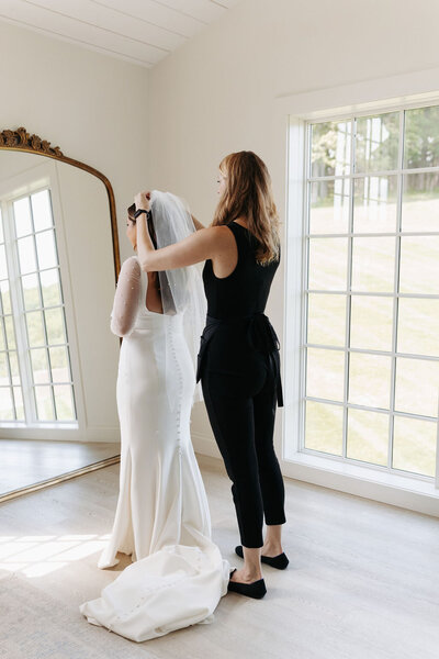 wedding planner adjusting bride's veil on wedding day