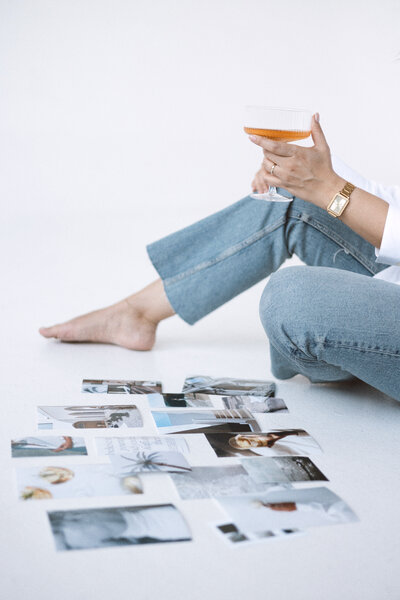 Amare Creative's brand styling featuring various photos on the ground, accompanied by a girl enjoying champagne."