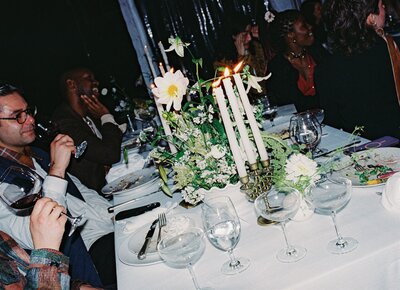 Candlelit wedding reception table with wild floral centerpiece, photographed on 35mm film | Organic, documentary-style wedding photography