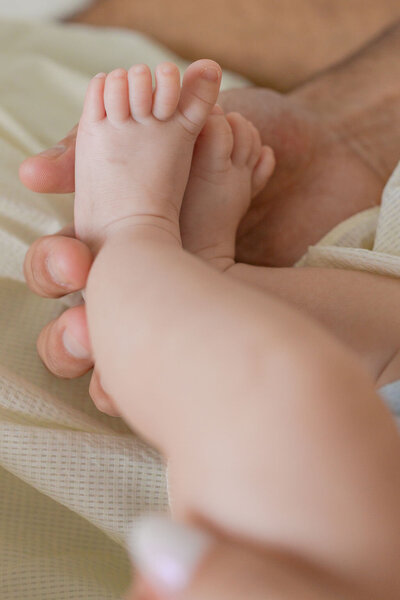 Close-up of a parent gently holding their baby’s tiny feet in their hands, capturing the delicate details of early parenthood.