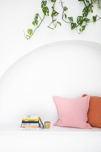 Melissa-Packham_A-Brand-Is-Not-A-Logo_arched-nook-with-pink-coral-cusions-books-coffee-cup-leafy-vine_Portrait