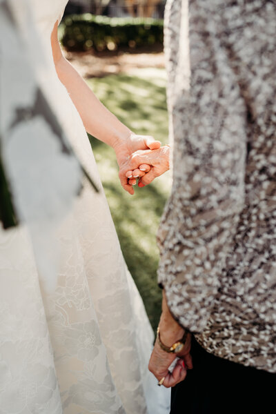 A heartfelt close-up capturing the hands of a bride and her grandmother on the wedding day—a timeless symbol of love, legacy, and generations intertwined. This emotional moment reflects the beauty of family bonds, reminding us that weddings are not just about the couple but also about the hands that have guided them along the way.