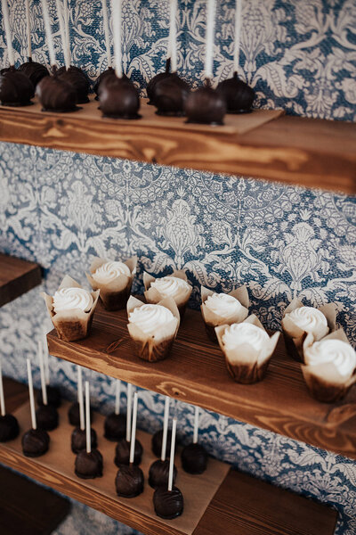 Wedding dessert wall with muffins and cake pops. wooden boards with blue wallpaper.
