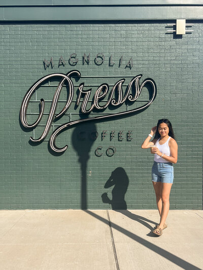 girl standing with coffee in front of the magnolia wall