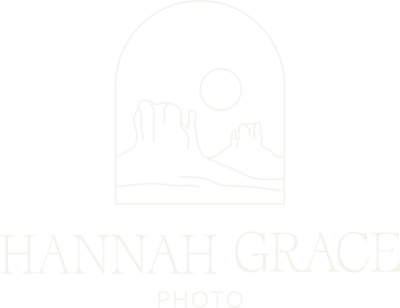 A white version of the Hannah Grace Photo logo. The Logo feautres a delicate handdrawn illustration of 2 buttes and the sun encased in an arch